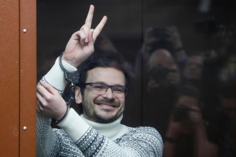 Russian opposition activist and former municipal deputy of the Krasnoselsky district Ilya Yashin gestures, smiling, as he stands in a defendant's cubicle in a courtroom, prior to a hearing in Moscow, Russia, on Dec. 9, 2022 (AP)