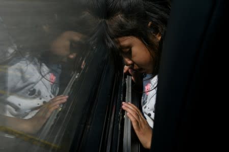 A migrant girl from Guatemala recently released with her mother from federal detention sits on a bus before its departure from a bus depot in McAllen