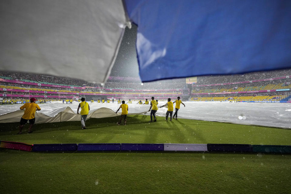 Ground staff pull covers as the rain delays the Indian Premier League cricket match between Rajasthan Royals and Kolkata Knight Riders in Guwahati, India, Sunday, May. 19, 2023. (AP Photo/Anupam Nath)