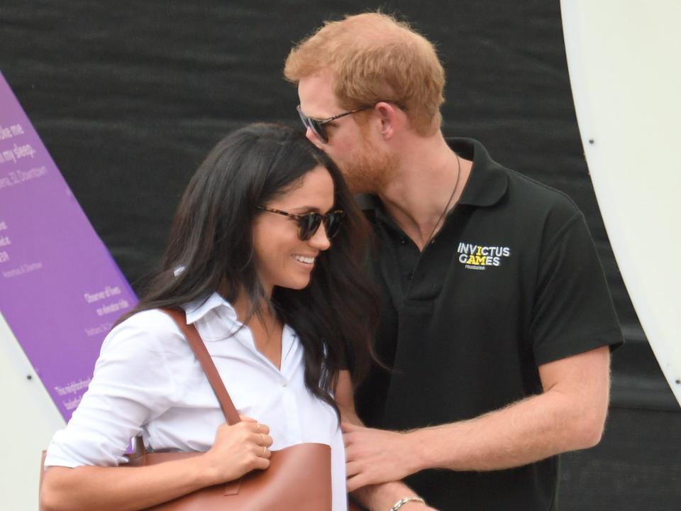 Prince Harry and Meghan Markle in 2017. Harry kisses Meghan on the forehead.