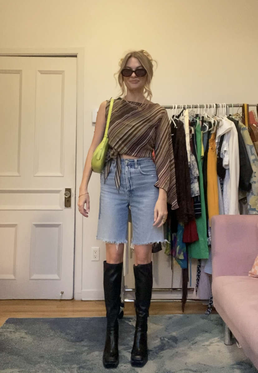 I am wearing an asymmetrical top, long jean shorts, high heeled black boots, a purse, sunglasses