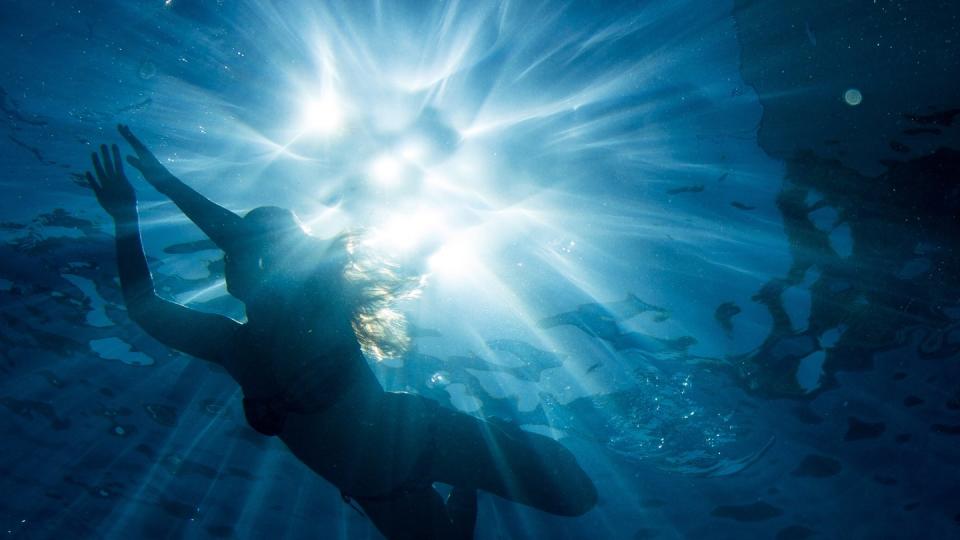 Ein Frau schwimmt bei strahlendem Sonnenschein im Freibad. (Bild: dpa)