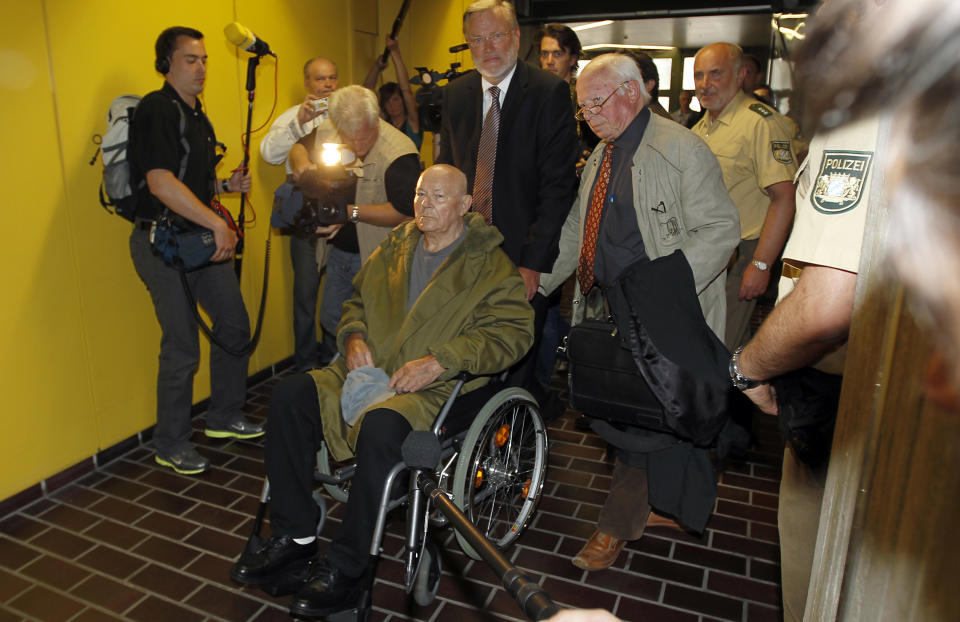 John Demjanjuk leaves the court room with his lawyers Ulrich Busch, center, and Guenther Maull, right, in Munich, southern Germany, on Thursday, May 12, 2011. The court has ordered John Demjanjuk released pending an appeal of his conviction as an accessory to murder at a Nazi death camp. (AP Photo/Matthias Schrader)