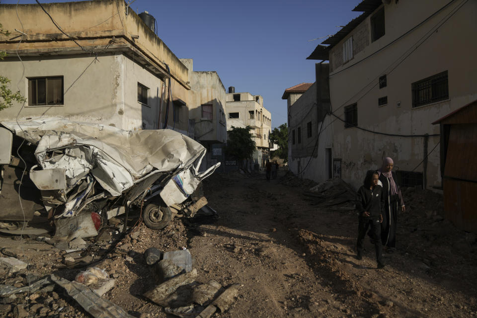 Palestinians walk on a damaged road in the Jenin refugee camp in the West Bank, Wednesday, July 5, 2023, after the Israeli army withdrew its forces from the militant stronghold. The withdrawal of troops from the camp ended an intense two-day operation that killed at least 13 Palestinians, drove thousands of people from their homes and left a wide swath of damage in its wake. One Israeli soldier was also killed. (AP Photo/Nasser Nasser)