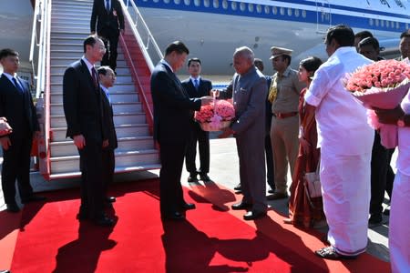 China's President Xi Jinping receives a bouquet upon his arrival at the airport in Chennai