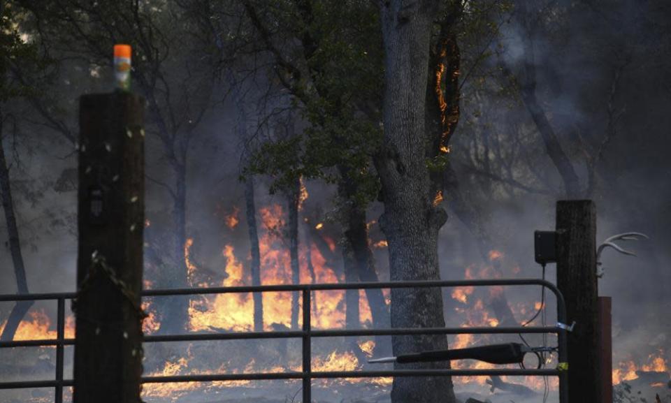 Flames from the Rices Fire burn near a home in rural North San Juan, California in June 2022.