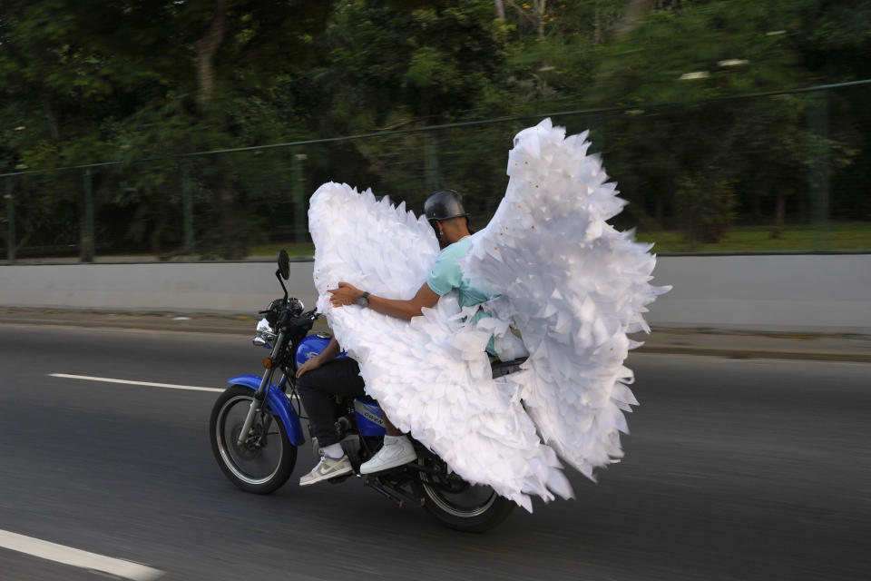 Una pareja lleva un par de alas de ángel en una moto durante el Carnaval, en Caracas, Venezuela, el 12 de febrero de 2024. (AP Foto/Ariana Cubillos)