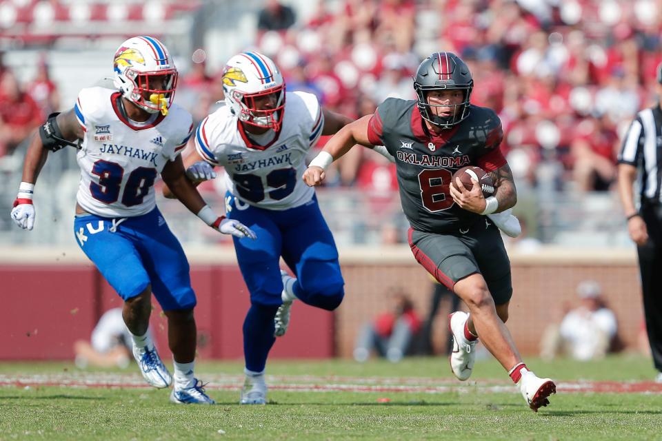 Oklahoma quarterback Dillon Gabriel (8) runs for a first down ahead of Kansas linebacker Rich Miller (30) and defensive lineman Malcolm Lee (99) during the second half of a game Saturday in Norman, Okla. Oklahoma won 52-42.