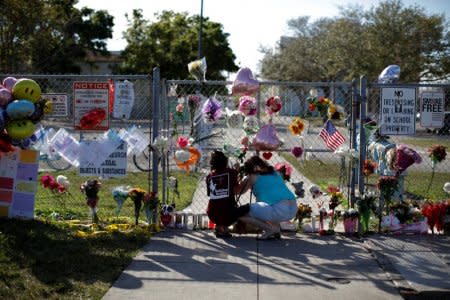 FILE PHOTO: People put flowers among other mementoes at the fence of the Marjory Stoneman Douglas High School, after the police security perimeter was removed, following a mass shooting in Parkland, Florida, U.S., February 18, 2018. REUTERS/Carlos Garcia Rawlins