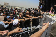 FILE - Protesters try to remove concrete barriers and cross the bridge towards the Green Zone area in Baghdad, Iraq, Saturday, July 30, 2022, as thousands of followers of an influential Shiite cleric breached the building for the second time in a week to protest the government formation efforts lead by Iran-backed groups. Iraq’s two rival Shiite political camps remain locked in a zero-sum competition, and the lone voice potentially able to end the rift — the revered Grand Ayatollah Ali al-Sistani — has been conspicuously silent. (AP Photo/Adil al-Khazali, File)