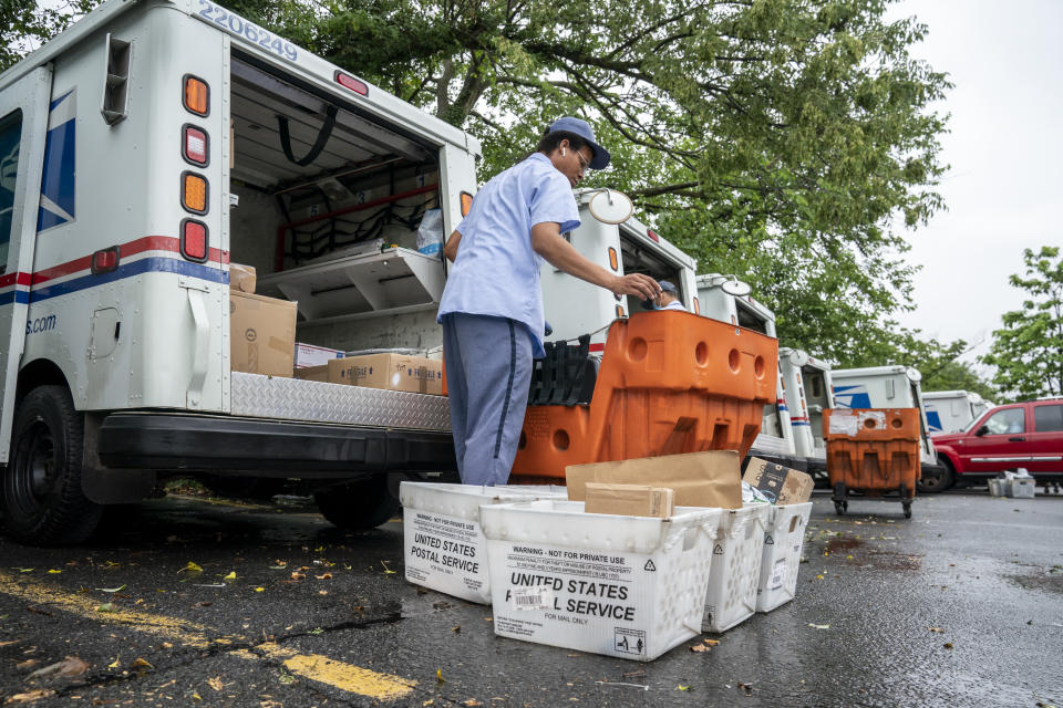 Letter carriers load mail trucks for deliveries at a U.S. Postal Service facility in McLean, Va., Friday, July 31, 2020. Delays caused by an increase in voting by mail may contribute to public doubts about the results. The public might not know the winner of the presidential race on Election Day because of a massive shift to voting by mail during the coronavirus pandemic. That’s because mail ballots take longer to count because of security procedures and laws in some states that limit when they can be processed. (AP Photo/J. Scott Applewhite)