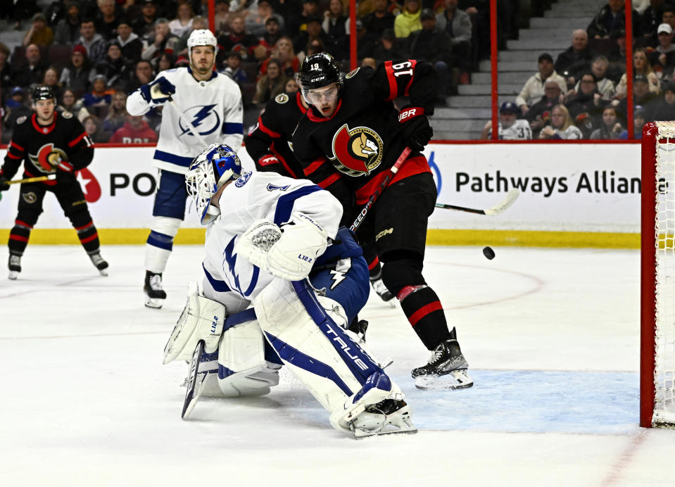 The puck bounces off the goalposts behind Tampa Bay Lightning goaltender Brian Elliott (1) and Ottawa Senators right wing Drake Batherson (19) during second-period NHL hockey game action in Ottawa, Thursday, March 23, 2023. (Justin Tang/The Canadian Press via AP)