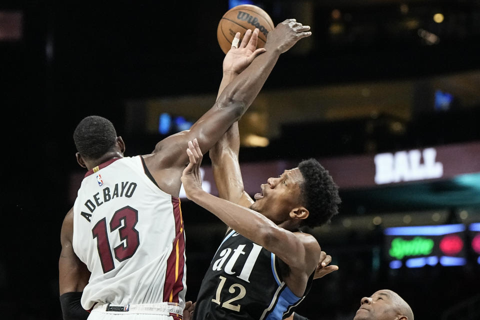 Miami Heat center Bam Adebayo (13) jumps for the ball against Atlanta Hawks forward De'Andre Hunter (12) during the second half of an NBA basketball game, Saturday, Nov. 11, 2023, in Atlanta. The Miami Heat won 117-109. (AP Photo/Mike Stewart)