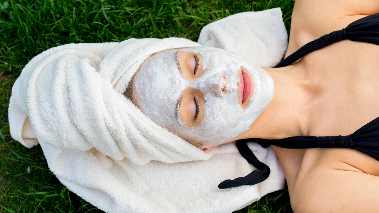 woman laying on grass with face mask