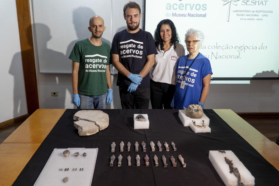 A group of archeologists pose with Egyptian recovered artifacts at the National Museum during a news conference in Rio de Janeiro, Brazil, Tuesday, May 7, 2019. Brazil's national museum said Tuesday it has recovered 200 pieces from its 700 pieces Egypt collection, the largest in Latin America, after a devastating fire in September 2018. (AP Photo/Lucas Dumphreys).