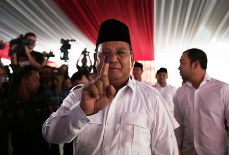 Indonesian presidential candidate Prabowo Subianto holds up his finger after voting at a polling station in Bogor July 9, 2014. REUTERS/Beawiharta