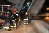 <p>In this image from TV, emergency services attend after a building collapsed on its side, as a man climbs a ladder to gain access to the building, centre background, after an early morning earthquake in Hualien County, eastern Taiwan, Feb. 7 2018. (Photo: EBC via AP) </p>