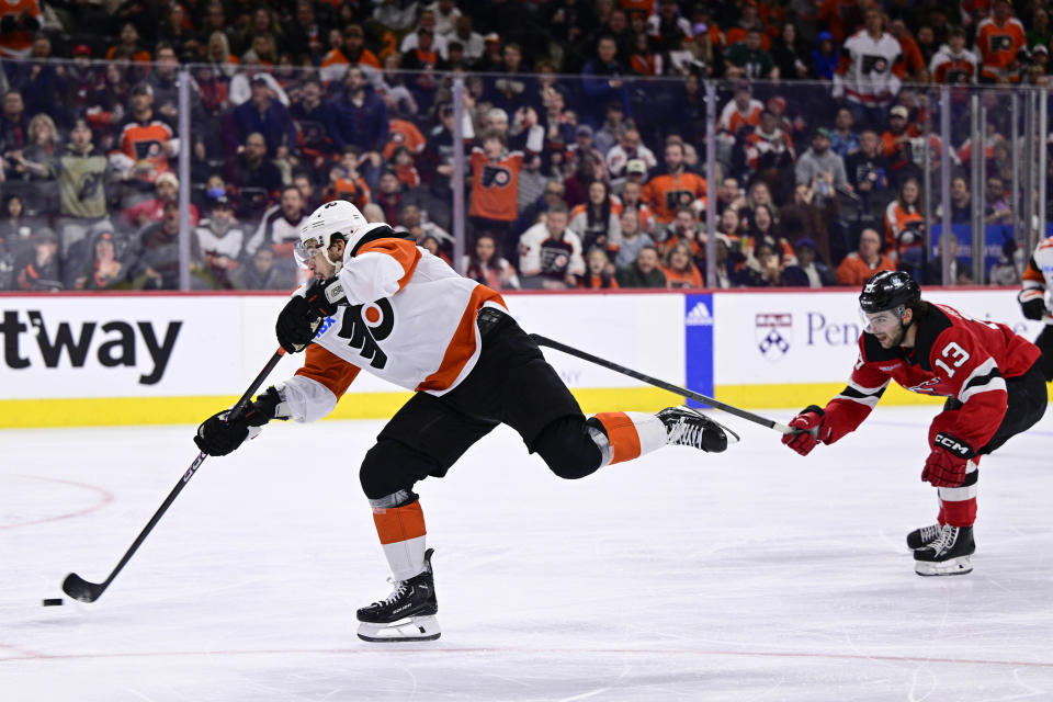 Philadelphia Flyers' Travis Konecny, left, shoots for a goal past the defense of New Jersey Devils' Nico Hischier (13) during the second period of an NHL hockey game, Saturday, April 13, 2024, in Philadelphia. (AP Photo/Derik Hamilton)