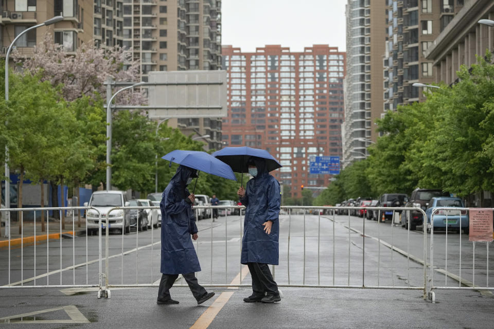 Security guards patrol along a barricaded road heading to locked-down communities on Wednesday, April 27, 2022, in Beijing. Workers put up fencing and police restricted who could leave a locked-down area in Beijing on Tuesday as authorities in the Chinese capital stepped up efforts to prevent a major COVID-19 outbreak like the one that has all but shut down the city of Shanghai. (AP Photo/Andy Wong)