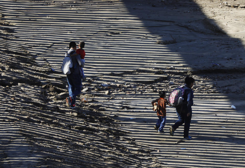 ADDS TO CLARIFY THAT COMPANIES ARE OPPOSING SHAREHOLDER VOTE ON PROPOSAL - FILE - In this Dec. 9, 2018, file photo, the striped shadow of the U.S. border wall falls on a migrant family as they walk on U.S. soil near Imperial Beach, Calif., after squeezing through a small hole under the border wall aided by two local guides, seen from Tijuana, Mexico. The nation's two largest private detention companies don't want a shareholder vote on resolutions that would prevent them from housing immigrant children separated from their parents, even though both companies say that is not something they currently do. (AP Photo/Rebecca Blackwell, File)