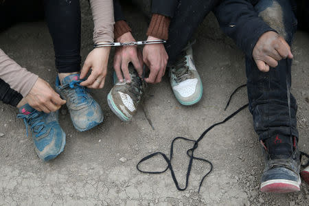 After being apprehended, immigrants who illegally crossed the border from Mexico into the U.S. follow directions from a border patrol agent to remove their shoelaces in the Rio Grande Valley sector, near McAllen, Texas, U.S., April 3, 2018. REUTERS/Loren Elliott