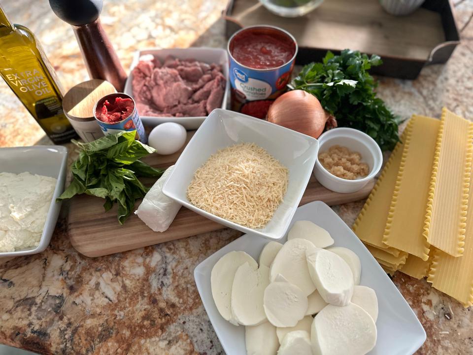 ingredients for ina garten's lasagna recipe, including cheese, tinned tomatoes, and lasagna noodles, arranged on a kitchen counter