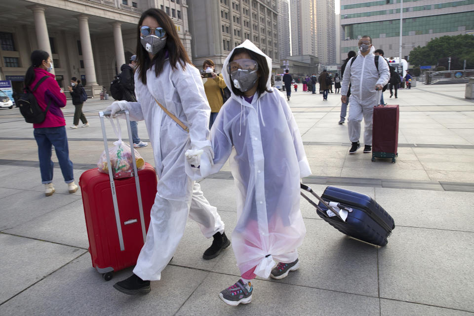 Passengers wearing face masks and rain coats to protect against the spread of new coronavirus walk outside of Hankou train station after of the resumption of train services (Ng Han Guan/AP)