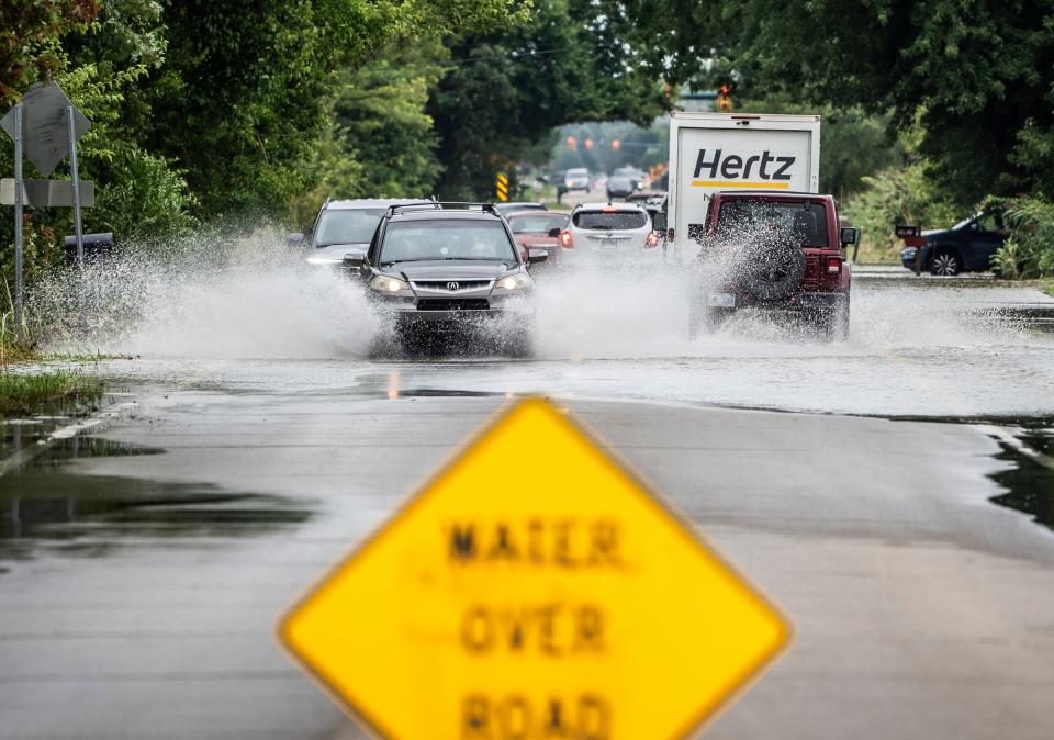 Cars drive through a flooded section of roadway on Geddes Road in Canton on Thursday, Aug. 24, 2023, after heavy rains brought flooding to multiple communities.