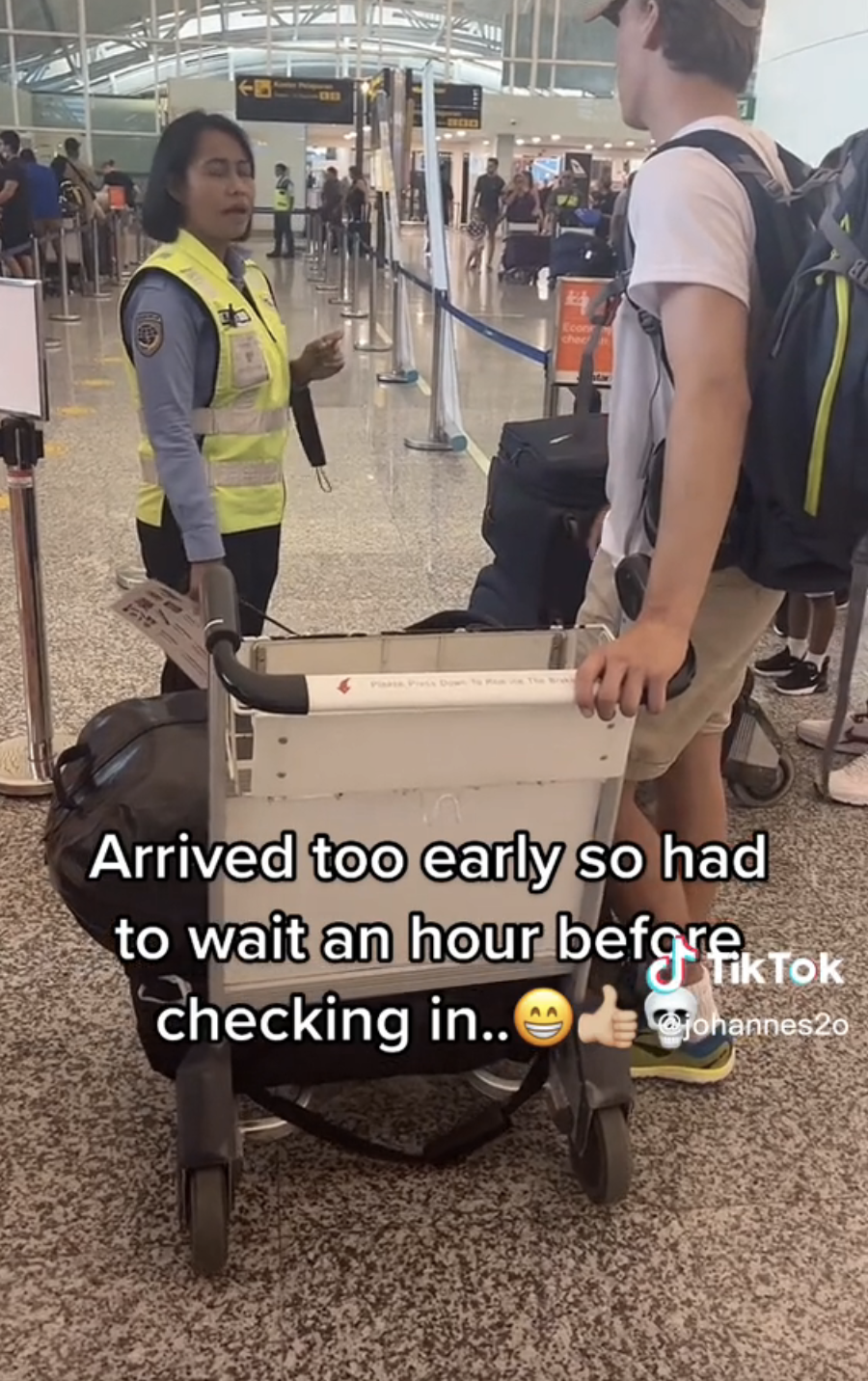 Rolv speaking to an airport agent with the caption, "Arrived too early so had to wait an hour before checking in" with grinning face, thumbs-up, and skull emojis