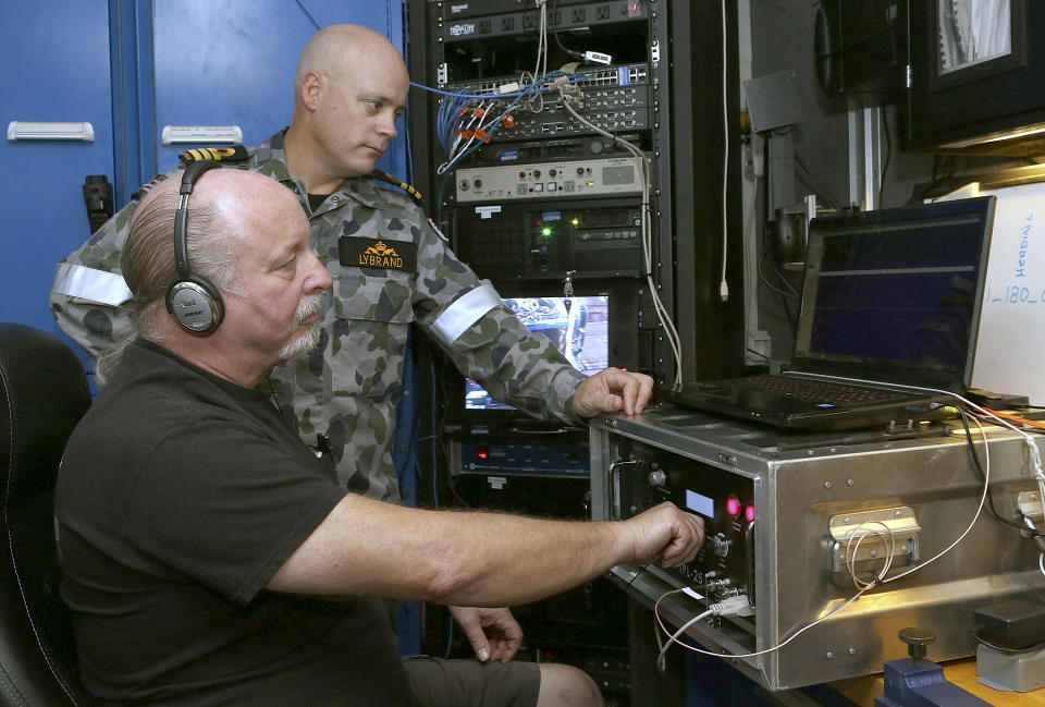 In this April 5, 2014, photo provided by the Australian Defense Force, Commander James Lybrand, left, watches as Mike Unzicker from Phoenix International monitors the feed from the towed pinger locator behind the Royal Australian Navy ship Ocean Shield in the southern Indian Ocean. Ocean Shield, which is carrying high-tech sound detectors from the U.S. Navy, is investigating a sound it picked up. (AP Photo/Australian Defense Force, Bradley Darvill) EDITORIAL USE ONLY