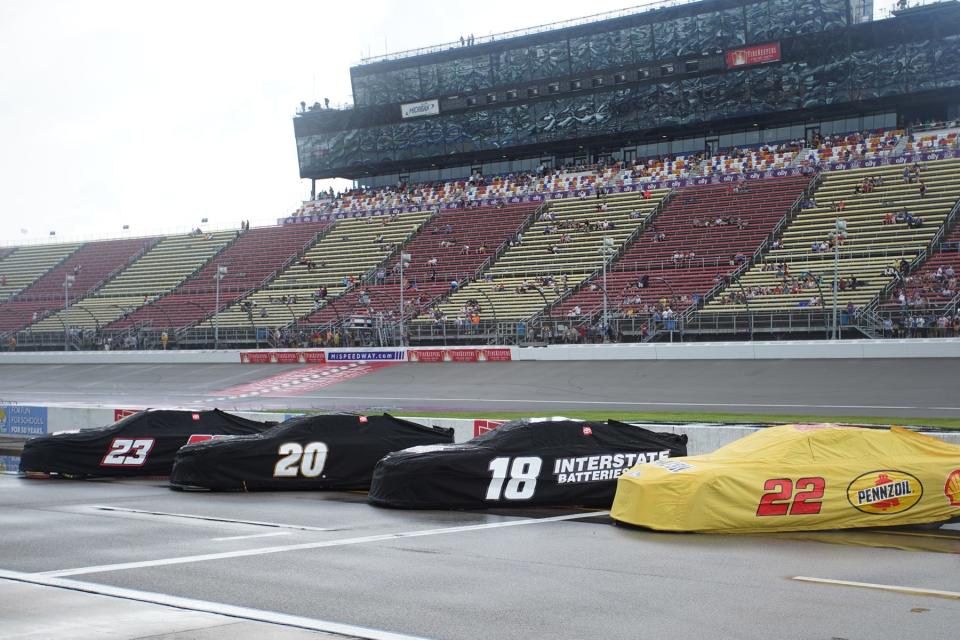 The cars sit covered on pit road as rain falls at Michigan International Speedway Sunday prior to the Firekeepers Casino 400 NASCAR Cup Series race.