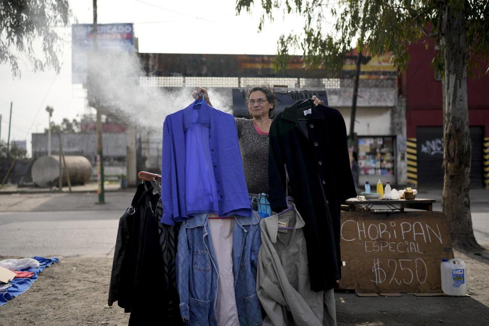 A vendor holds up secondhand garments at a market where people can buy or barter goods, on the outskirts of Buenos Aires, Argentina, Wednesday, Aug. 10, 2022. Argentina has one of the world’s highest inflation rates, currently running at more than 60% annually, according to the National Institute of Statistics and Census of Argentina (INDEC). (AP Photo/Natacha Pisarenko)