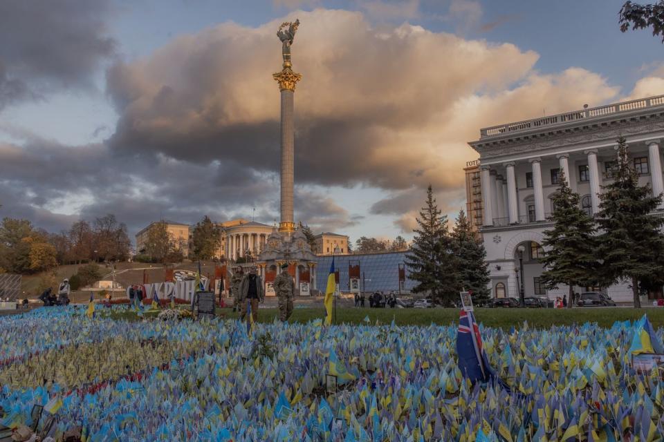 Pedestrians wearing military uniforms walk past flags bearing symbols and colors of Ukraine that commemorate fallen Ukrainian soldiers at Independence Square in Kyiv on Oct. 23, 2023, amid the Russian invasion of Ukraine. (Roman Pilipey/AFP via Getty Images)