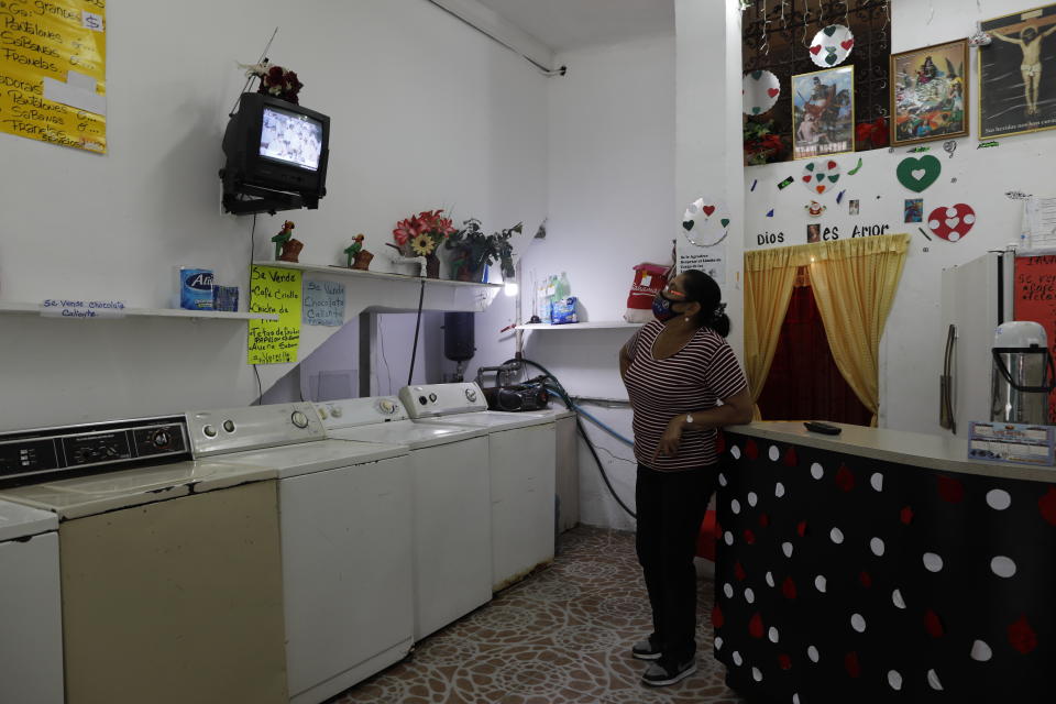 Maria Comedor watches a live television broadcast of the Beatification ceremony for the late, Venezuelan Dr. Jose Gregorio Hernandez inside her washateria she operates in Caracas, Venezuela, Friday, April 30, 2021. Known as the "doctor of the poor, Hernandez is being Beatified by the Catholic church, a step towards sainthood. (AP Photo/Ariana Cubillos)