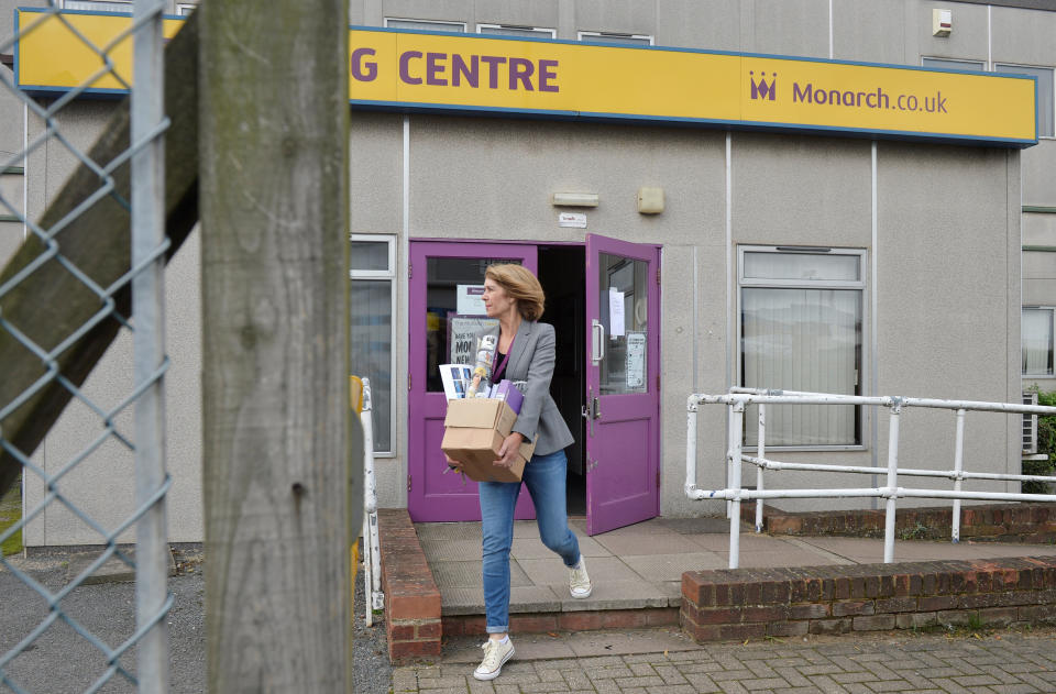 A woman carries a cardboard box out of a Monarch office after the airline ceased trading, at Luton airport in Britain, October 2, 2017. REUTERS/Mary Turner