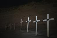 Crosses mark graves at the cemetery in Longyearbyen, Norway, Wednesday, Jan. 11, 2023. The cemetery, established in 1917 for miners -- at least 124 died on duty since then -- is now considered in the "danger zone" from increasing avalanches and landslides. A new burial ground is in the works, though the approximately 30 old graves will not be moved, the Rev. Liv Simstrand said. (AP Photo/Daniel Cole)