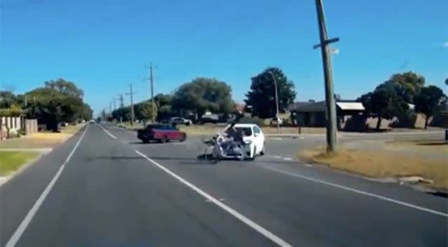 The rider is struck, and the impact causes him to fall off his bike. Source: Dash Cam Owners Association/Facebook