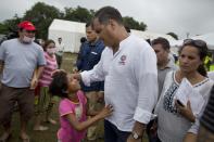 ARCHIVO - En esta foto de archivo del 22 de abril de 2016 el presidente de Ecuador, Rafael Correa, escucha a una niña durante una visita a un campamento improvisado para personas sin hogar por el terremoto de 7,8 grados de magnitud en Pedernales. (AP Foto/Rodrigo Abd, Archivo)