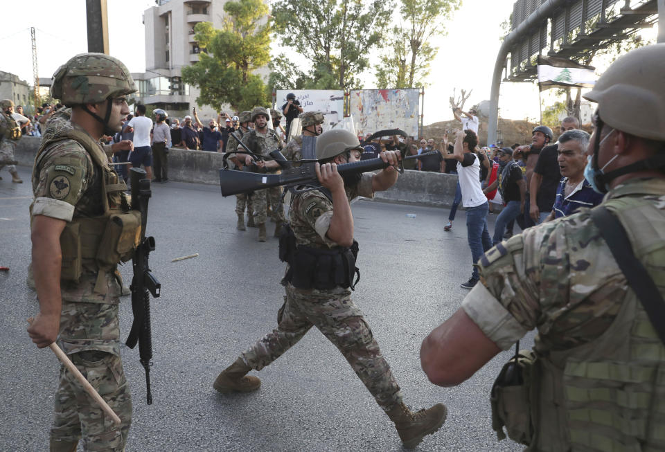 A Lebanese army soldier uses his rifle to push back the anti-government protesters, during a protest against the Lebanese President Michel Aoun near the presidential palace, in Baabda east of Beirut, Lebanon, Saturday, Sept. 12, 2020. Soldiers fired rubber bullets and live rounds in the air to disperse hundreds of protesters trying to march to the presidential palace during an anti-government demonstration. (AP Photo/Bilal Hussein)