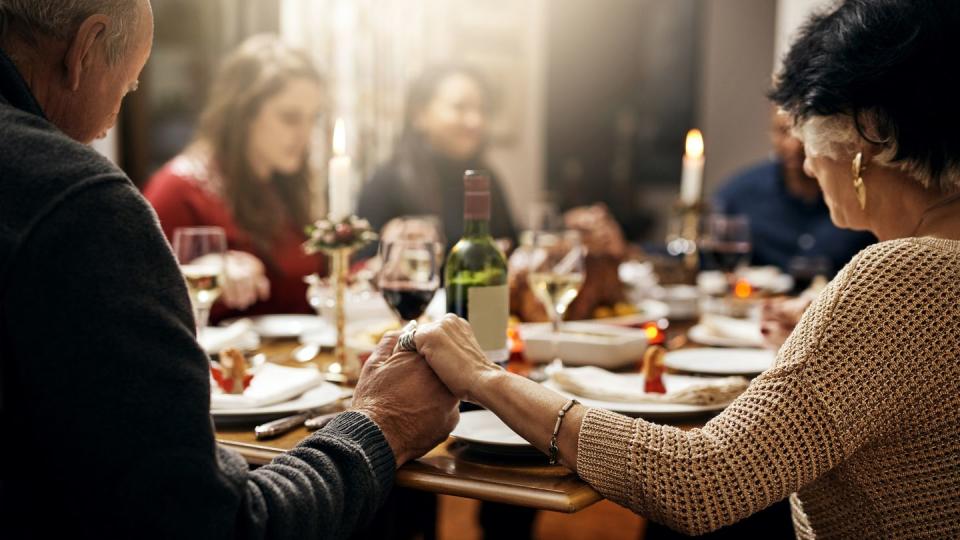 shot of family holding hands in prayer before having a christmas lunch together