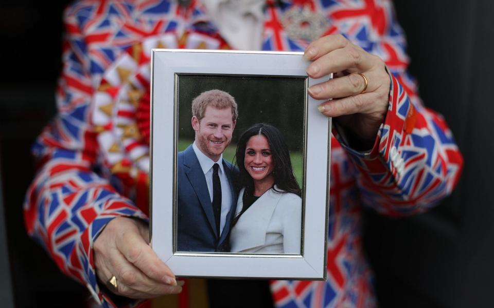 Royal fan Margaret Tyler poses for a photograph holding a framed picture of Prince Harry and Meghan Markle - AFP/ DANIEL LEAL-OLIVAS