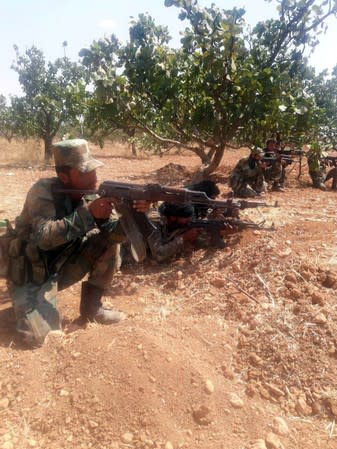 Syrian army soldiers hold their weapons in Idlib countryside