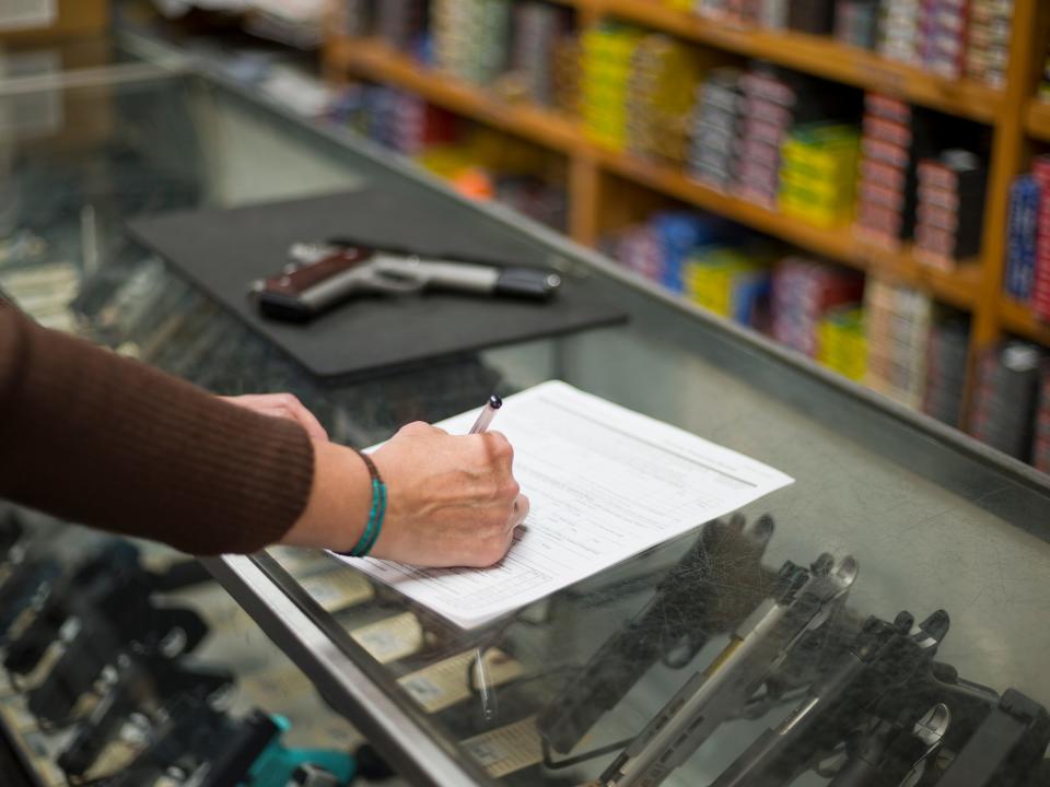 A woman fills out ATF U.S. Dept. of Justice application paperwork for gun at a gun shop in Colorado.