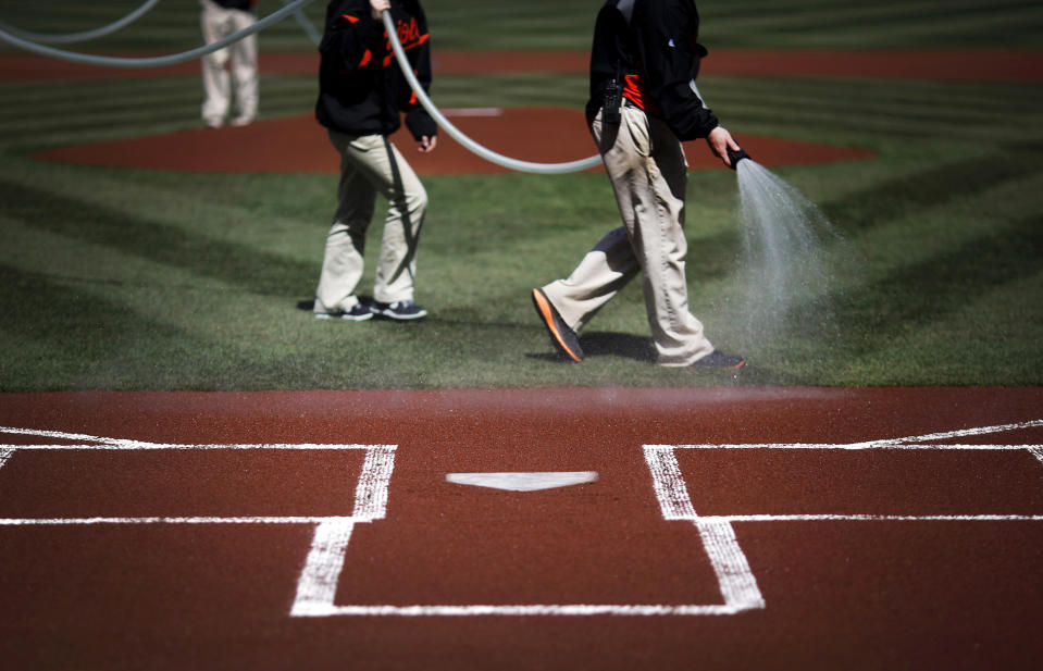 Members of the grounds crew water the infield before an opening day baseball game between the Baltimore Orioles and the Boston Red Sox, Monday, March 31, 2014, in Baltimore. (AP Photo/Patrick Semansky)