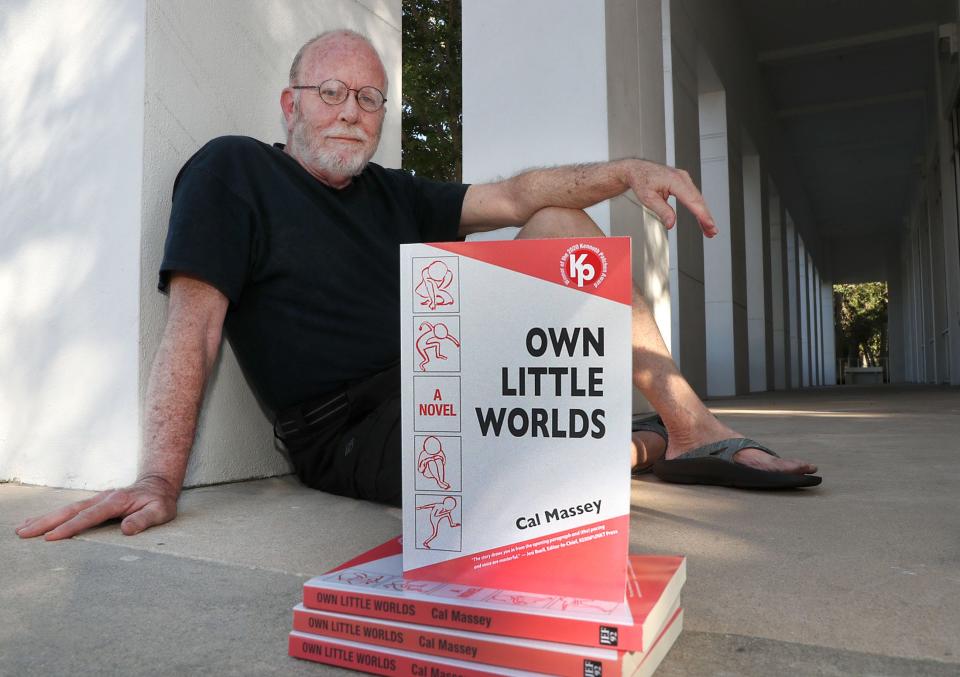 Flagler Beach author Cal Massey is pictured with his first novel, "Own Little Worlds," outside the Ormond Beach Regional Library, where he did much of his writing. It's a fast-paced fictional ride through post-Trump America with characters caught in a swirl of false truth and a democracy crumbling under the weight of the American divide. "The book is offbeat and angry but there's a pretty good political thriller plot in there, too, with the lost art of legitimate journalism in pursuit,” Massey said.