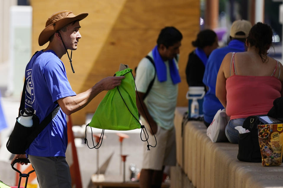 The City of Phoenix Heat Response Program team volunteer Sean Hetzel hands out heat relief packages as temperatures are expected to hit 119-degrees Thursday, July 20, 2023, in Phoenix. (AP Photo/Ross D. Franklin)