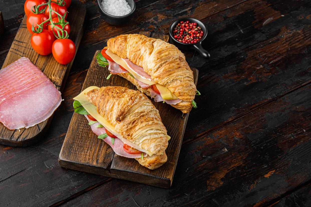 Croissant with ham set, with herbs and ingredients, on old dark  wooden table background, with copy space for text