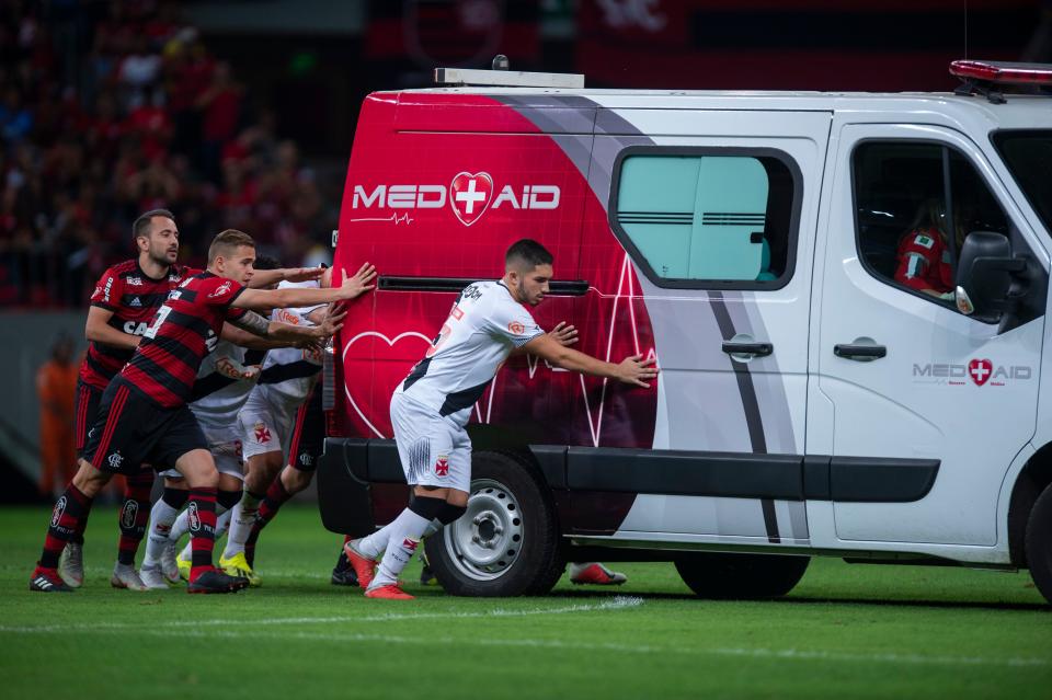 Flamengo and Vasco da Gama players push the ambulance carrying Bruno Silva after it’s engine failed to start on the field during the second half of their Brazilian national championship match at Mane Garrincha stadium in Brasilia