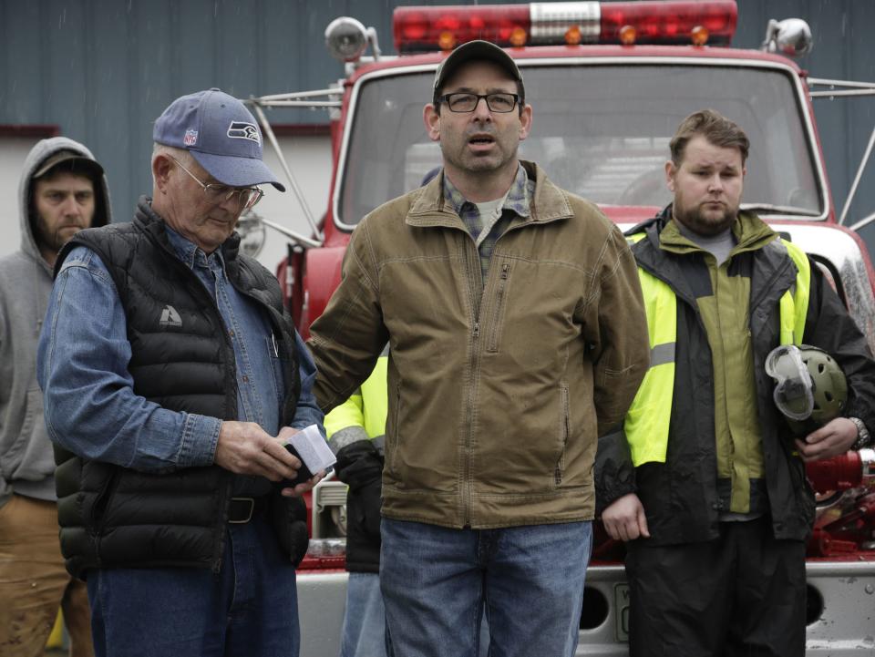 Darrington Mayor Dan Rankin (2nd R) and Pastor Mike De Luca (2nd L) lead workers and community members in prayer and a moment of silence marking the one-week anniversary of the Oso landslide at the fire station in Darrington, Washington March 29, 2014. The grim task of combing through debris from a mudslide that obliterated dozens of homes on the outskirts of a rural Washington town came to a standstill briefly on Saturday for a moment of silence. The somber moment at 10:37 a.m. (1737 GMT) was observed exactly one week after the catastrophe, amid uncertainty over the fate of 90 people still listed as missing. On Friday, the body count was at 27. REUTERS/Jason Redmond (UNITED STATES - Tags: DISASTER ENVIRONMENT POLITICS)