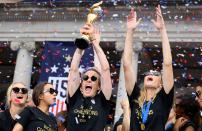 USA women's soccer player Megan Rapinoe (C) and other team members celebrate with the trophy in front of the City Hall after the ticker tape parade for the women's World Cup champions on July 10, 2019 in New York. - Tens of thousands of fans are poised to pack the streets of New York on Wednesday to salute the World Cup-winning US women's team in a ticker-tape parade. Four years after roaring fans lined the route of Lower Manhattan's fabled "Canyon of Heroes" to cheer the US women winning the 2015 World Cup, the Big Apple is poised for another raucous celebration. (Photo by Johannes Eisele/AFP/Getty Images)